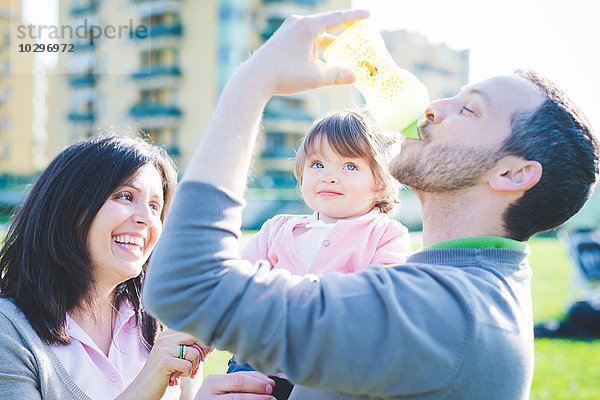 Mittlerer Erwachsener Mann trinkt Kleinkind Töchter Babyflasche im Park