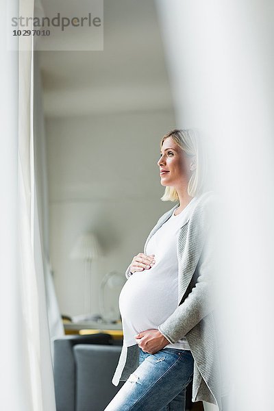 Vollzeitschwangerschaft junge Frau blickt aus dem Fenster