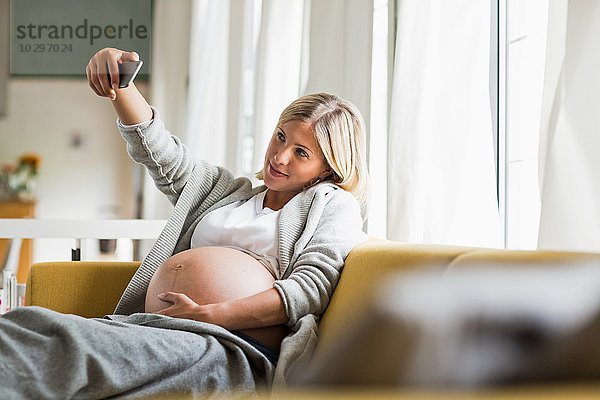 Vollzeit-Schwangerschaft junge Frau auf dem Sofa unter Selfie
