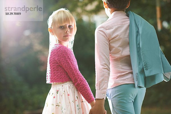 Mädchen schaut über die Schulter und hält die Jungen im Garten.