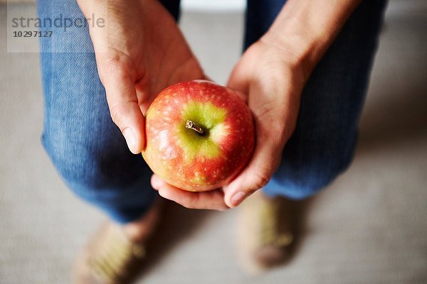 Draufsicht auf Frauenhände mit rotem Apfel