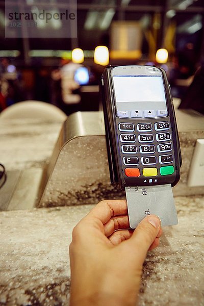 Womans Hand mit Kreditkarte Maschine für die Zahlung im Restaurant