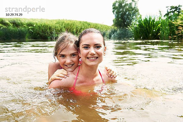 Porträt eines Mädchens und einer Schwester  die im See schwimmen.