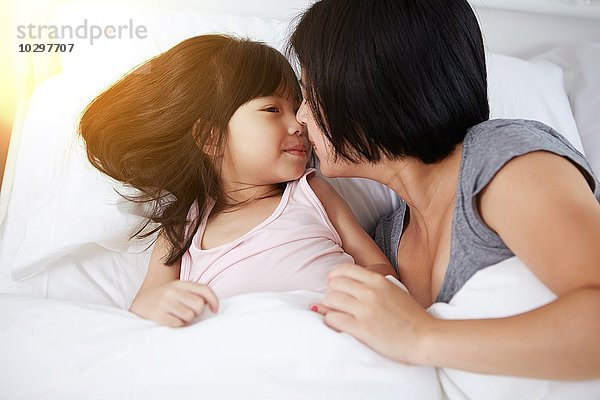 Junge chinesische Mutter und Tochter liegen zusammen zu Hause im Bett.