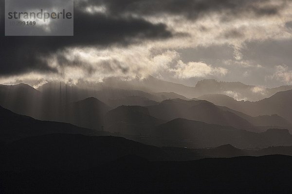 Tiefhängende Wolken  Gewitterwolken mit durchdringenden Sonnenstrahlen  hügeliche Landschaft  dramatische Lichtstimmung und Wolkenstimmung  bei Agüimes  Gran Canaria  Kanarische Inseln  Spanien  Europa