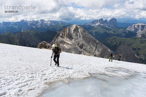 Bergsteiger überqueren Schneefeld am Gipfel Punta Penia  Marmolata  hinten die Langkofelgruppe  Dolomitan  Alpen  Trentino-Alto Adige  Südtirol  Italien  Europa