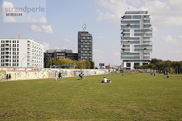 Menschen im ehemaligen Todesstreifen an der East Side Gallery  neues Luxus-Appartementhaus hinten  Berlin  Deutschland  Europa