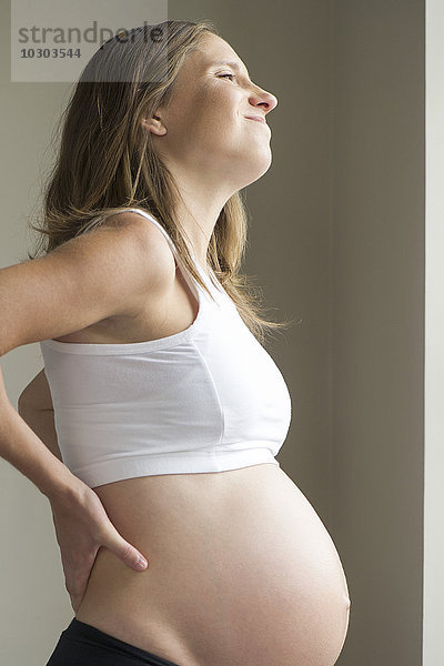 Schwangere Frau beim Massieren des unteren Rückens
