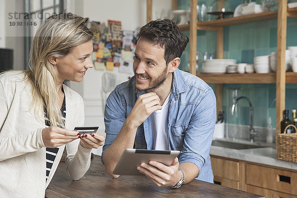 Paar mit digitalem Tablett zum Online-Shopping zu Hause