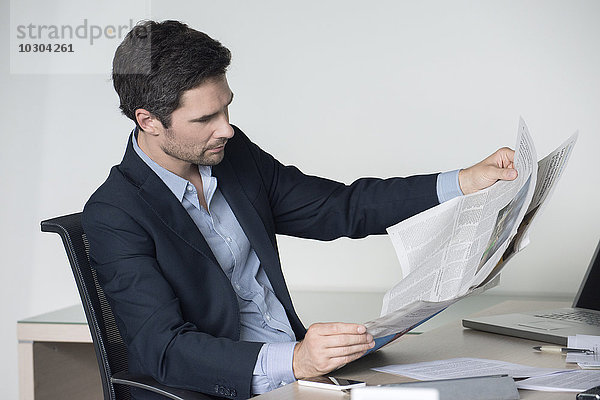 Geschäftsmann liest Zeitung im Büro