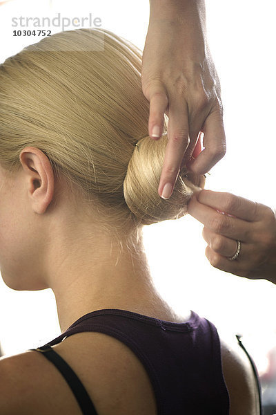 Friseur arrangiert Frauenhaar in einem Chignon  geschnitten