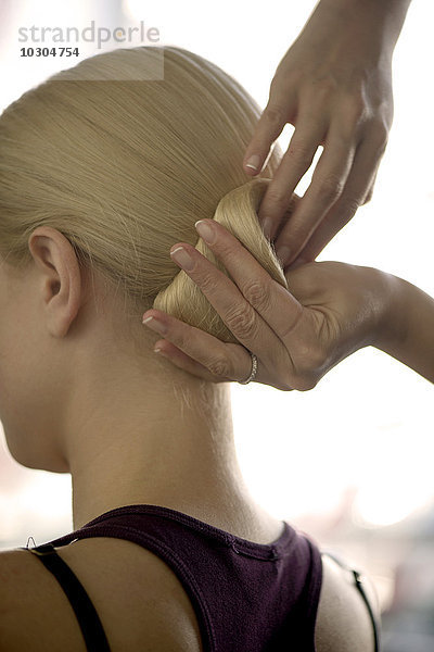 Friseur arrangiert Frauenhaar in einem Chignon  geschnitten