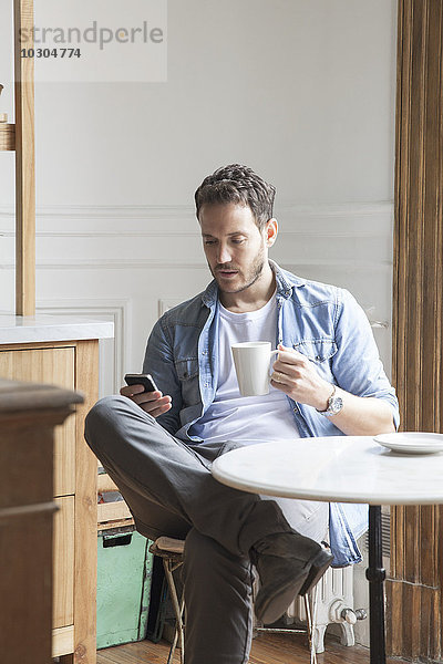 Mann sendet SMS während der Kaffeepause