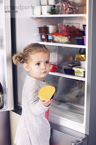 Kleines Mädchen  das Essen aus dem Kühlschrank holt.