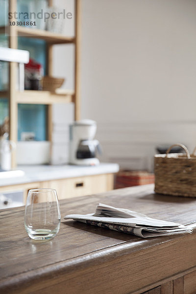 Leeres Weinglas und Zeitungspapier auf der Küchentheke