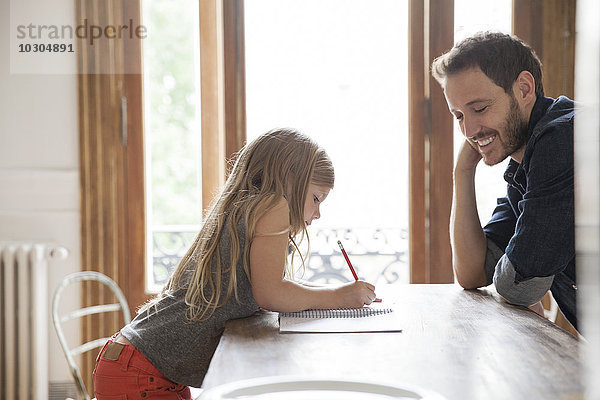 Vater hilft Tochter beim Schreiben