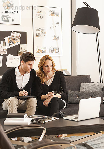 Paar zuhause  sitzt auf Couch vor Laptop