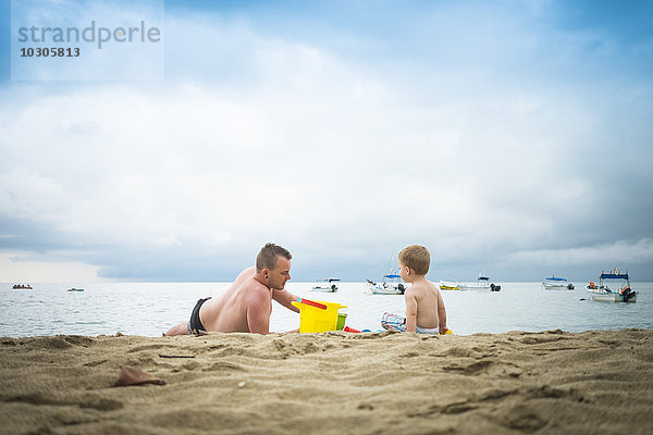 Mexiko  Vater spielt mit seinem kleinen Sohn im Sand an einem Strand.