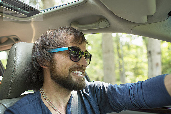 Ein Mann mit Sonnenbrille auf dem Fahrersitz eines Autos.