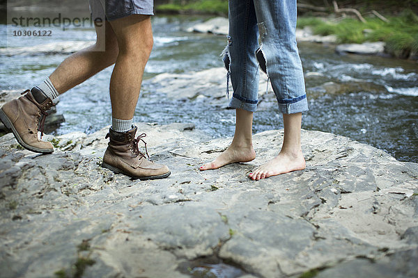 Zwei Menschen auf den Felsen an einem rauschenden Fluss  Mann und Frau  Unterschenkel und Füße.