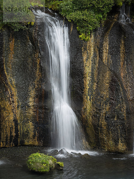 Hraunfossar-Wasserfälle  eine Wasserkaskade über eine steile Klippe in ein Becken.