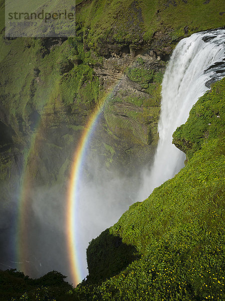 Wasserfall Skogafoss mit einem doppelten Regenbogen im Nebel und Dampf  der aus dem Wasser aufsteigt.