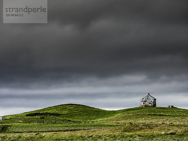 Eine Scheune auf dem Kamm eines Hügels und dunkle Gewitterwolken  die über dem Land glühen.