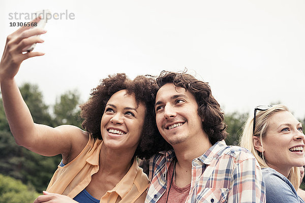 Ein junges Paar  ein Mann und eine Frau  die mit einem Smartphone einen Selfie machen.