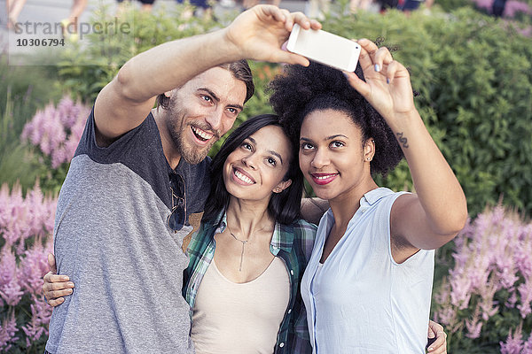 Zwei Frauen und ein Mann posieren für ein Selfie