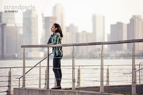 Eine Frau steht am Wasser  Blick auf die Stadt über dem Wasser in New York City.