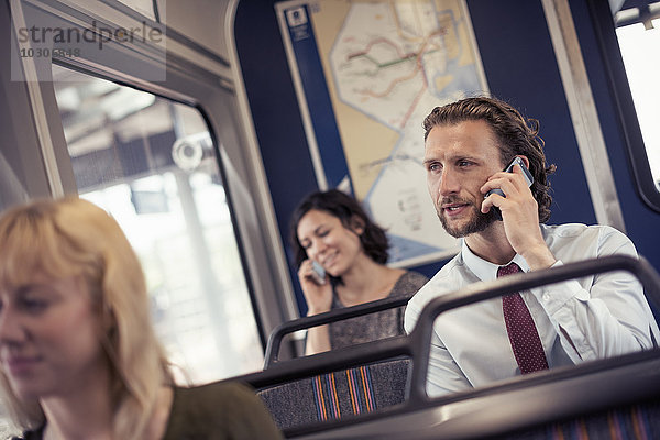 Drei Personen in einem Bus  zwei telefonieren mit ihren Handys
