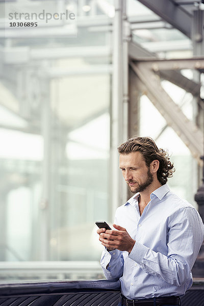 Ein Mann steht draußen auf der Straße und überprüft sein Mobiltelefon.