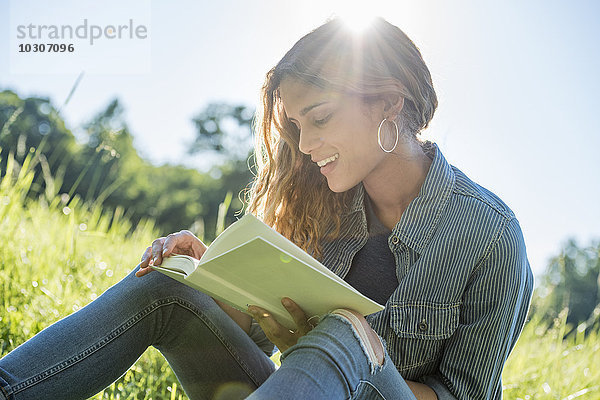 Eine junge Frau sitzt in der Sonne und liest ein Buch