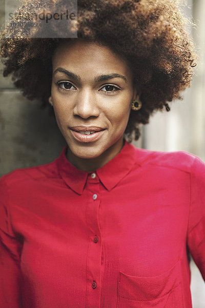 Porträt einer lächelnden jungen Frau in roter Bluse