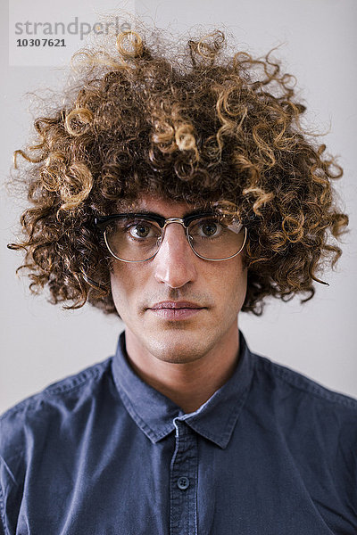 Porträt eines ernsthaft aussehenden Mannes mit lockigem Haar und Brille