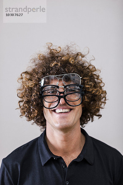 Porträt eines lächelnden Mannes mit lockigem Haar in vier verschiedenen Brillen