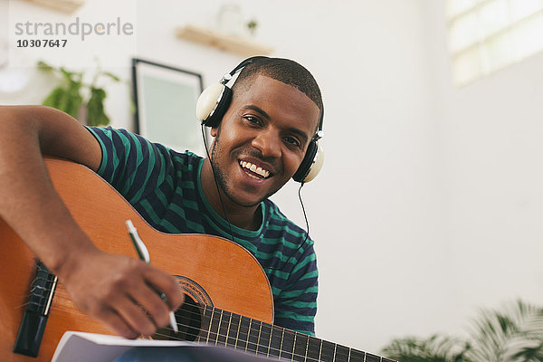 Porträt eines lächelnden Mannes mit Gitarrenmusik mit Kopfhörer