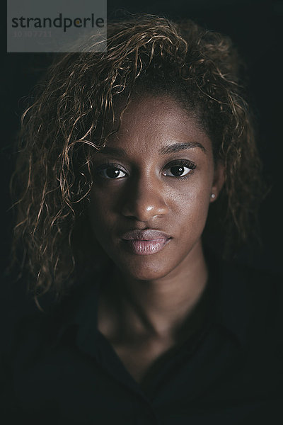 Porträt einer attraktiven jungen Frau vor schwarzem Hintergrund