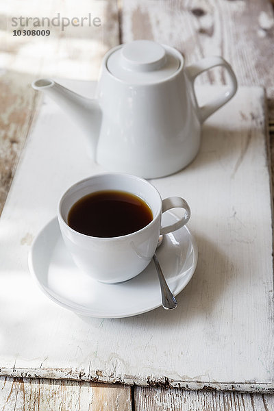 Tasse schwarzer Kaffee und Kaffeekanne auf Holz