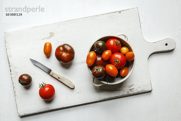 Verschiedene Tomaten  Zebrino  Ebeno  Devotion und gelbe Kirschtomaten auf Hackbrett  Küchenmesser  Schüssel