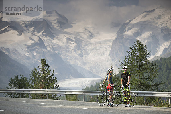 Schweiz  Engadin  zwei Radfahrer auf der Berninapassstrasse vor dem Morteratschgletscher