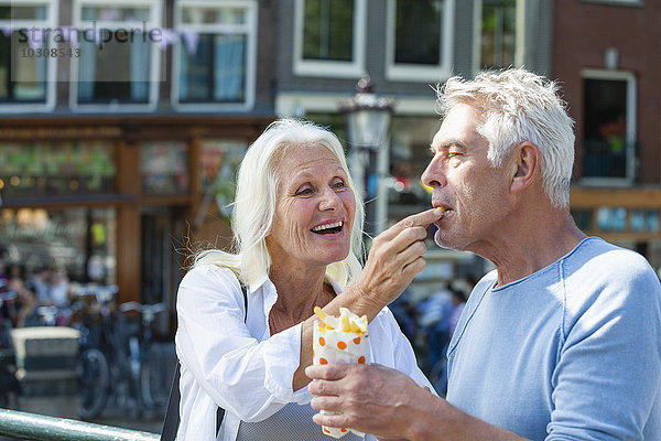 Niederlande  Amsterdam  glückliches Seniorenpaar beim Pommes Frites essen