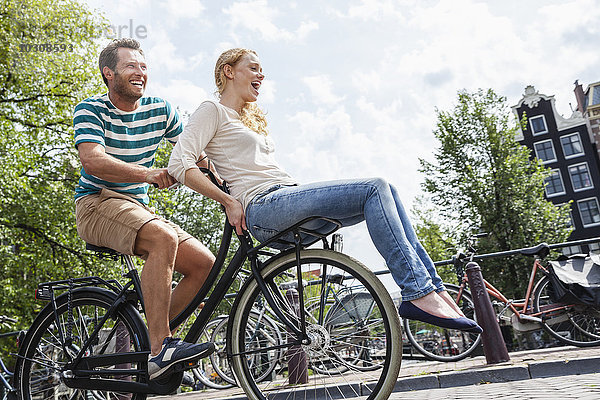 Niederlande  Amsterdam  glückliches Paar beim Fahrradfahren in der Stadt