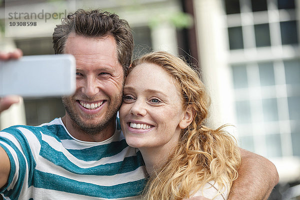 Lächelndes Paar mit einem Selfie im Freien
