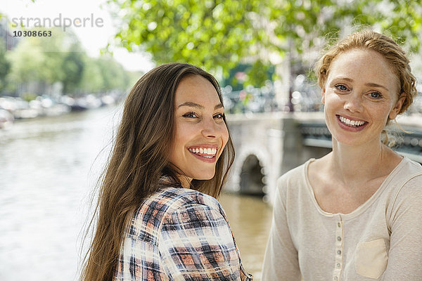 Niederlande  Amsterdam  zwei lächelnde Frauen am Stadtkanal