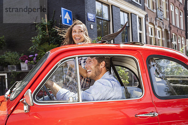 Niederlande  Amsterdam  glückliches Paar mit kleinem Auto in der Stadt