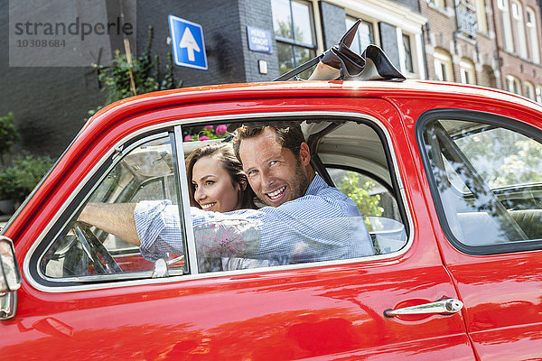 Niederlande  Amsterdam  glückliches Paar mit kleinem Auto in der Stadt