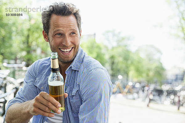 Niederlande  Amsterdam  glücklicher Mann trinkt Bier aus der Flasche