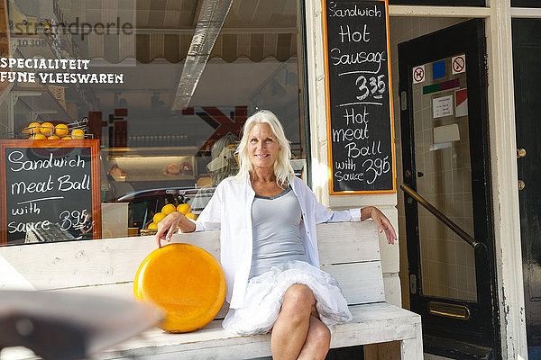 Niederlande  Amsterdam  Seniorin sitzend auf Bank mit Käsebrot