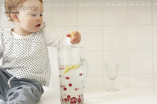Kleines Mädchen nimmt Zitronenscheiben aus der Wasserkaraffe